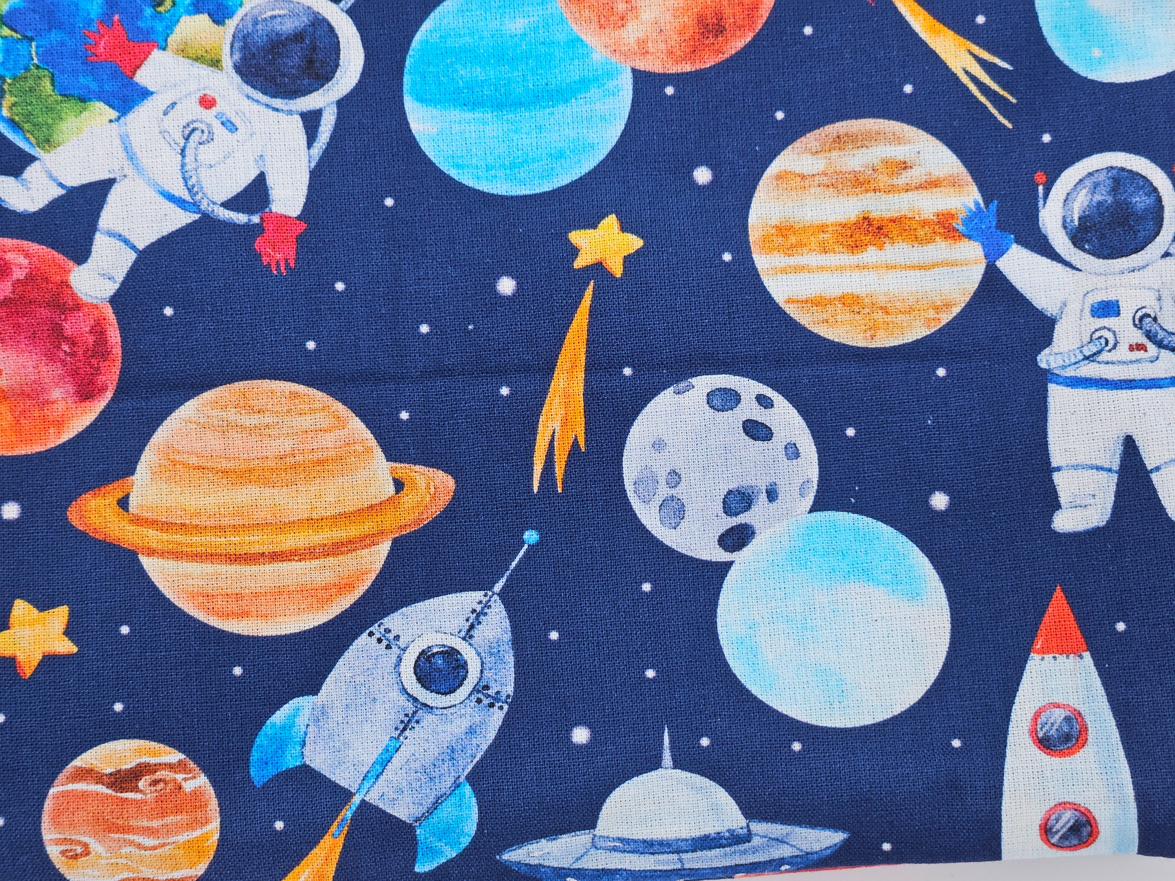 Pattern of a space-themed design including astronauts, planets, and rockets on a blue background.