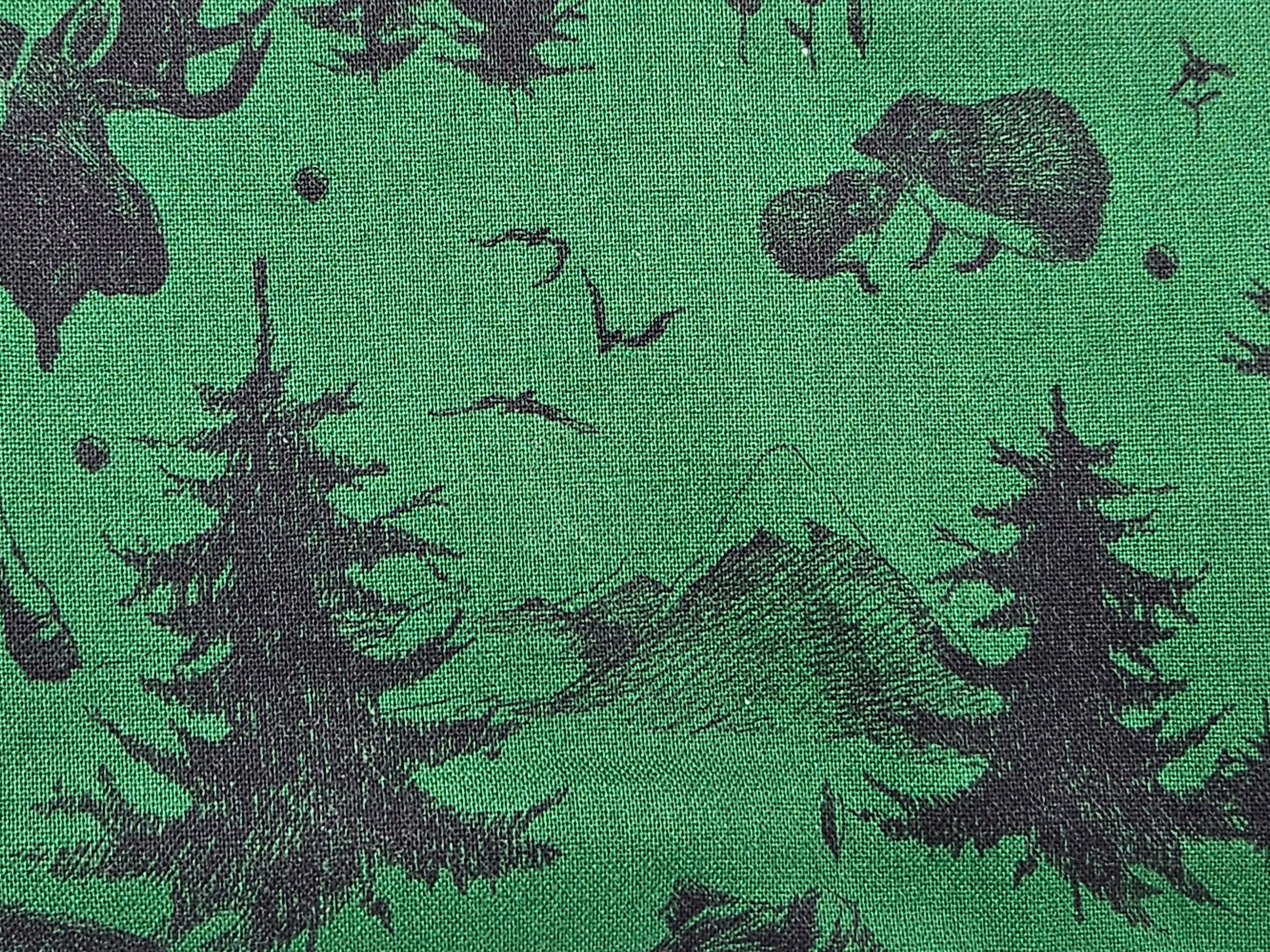 Green fabric with black forest pattern including trees, deer, and mountains.